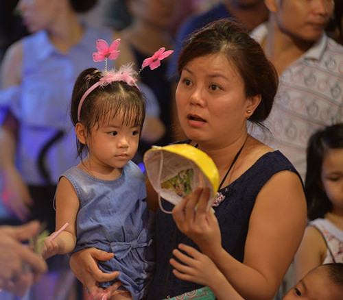 Một phụ huynh đang chọn mua một chiếc mặt nạ giấy cho cô con gái nhỏ.