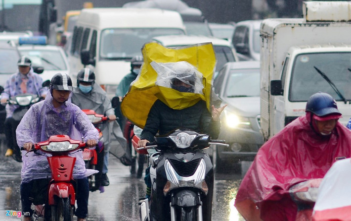 Người phụ nữ khác khi lái xe máy ở tốc độ khoảng 40 km/h giữa dòng người đông đúc đã bị gió hất tung áo mưa che mặt mất vài giây, khá nguy hiểm. Ảnh: Tiến Tuấn.