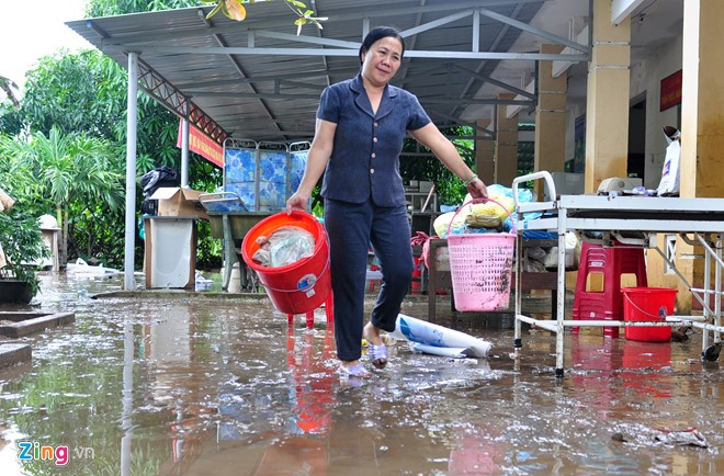 Bà Phạm Thị Luận, Phó trạm Y tế xã An Hiệp dọn dẹp bùn đất sau trận lũ quét. "Tôi đang trực ở cơ quan thì nghe nước chảy rào rào, tích tắc lũ dâng lên ngập đến nửa trạm. Thấy lũ lớn nhanh, tôi sợ quá liền mặc áo phao vào rồi cấp tốc điện thoại cầu lãnh đạo xã. Lực lượng cứu hộ đã dùng dây thừng buộc vào cơ thể rồi chia nhau kéo, dìu tôi thoát ra vùng ngập sâu nguy hiểm", bà Luận nói.