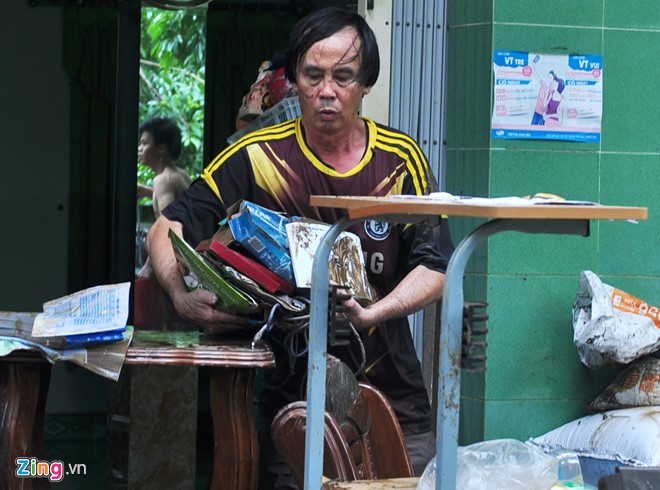 Người dân lấm lem bùn đất vất vả dọn dẹp đồ đạc.