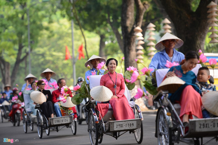 Màn diễu hành với sự tham gia của 50 xe xích lô chở 50 nghệ sĩ, người mẫu, trẻ em mặc áo dài và 100 nữ sinh đi xe đạp hoa. NSND Thu Quế đằm thắm trong tà áo dài đỏ trong đoàn xích lô xuất phát từ phố Hoàng Diệu.
