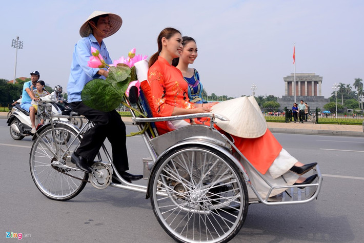 50 xe xích lô chở người mẫu mặc áo dài theo sau đoàn thiếu nữ đi xe đạp.