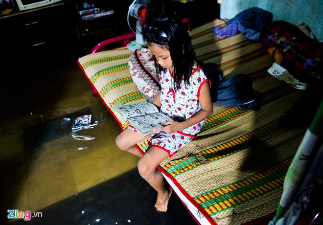 Cuộc sống đảo lộn ảnh hưởng tới học tập, sinh hoạt của cả người lớn lẫn trẻ nhỏ. Trong ảnh là bé Thạch Kiều My ngồi đọc truyện tranh trong nhà đầy nước.