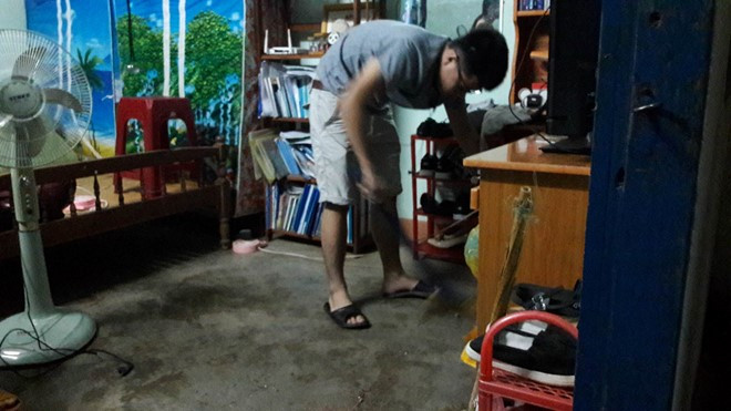 Một người dân cặm cụi dọn dẹp căn nhà vương vãi vụn kính.