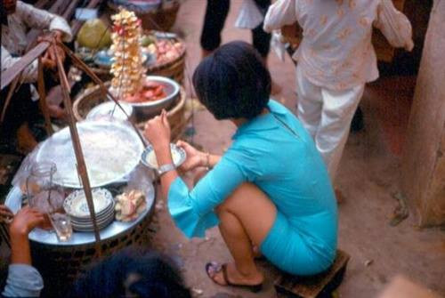 Một quý cô không ngại ngồi bệt thưởng thức món ăn hè phố.