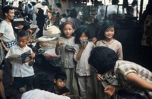 Trẻ em thưởng thức đồ ăn vặt và khá tò mò khi ống kính chụp hình hướng về phía mình.
