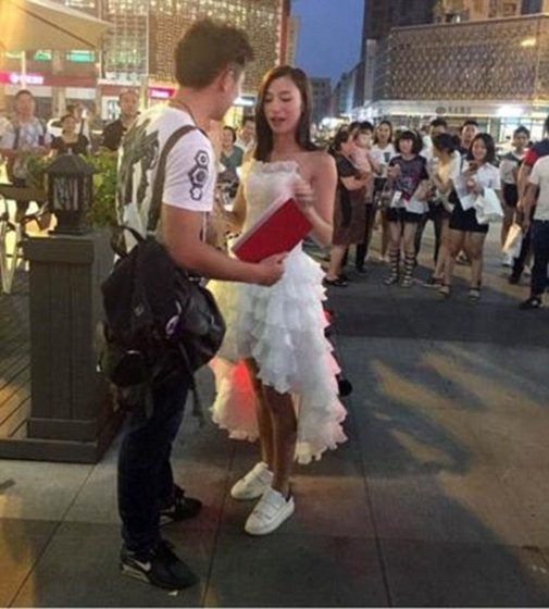 Cuối tháng 8/2016, dân mạng cũng ngỡ ngàng vì màn cầu hôn bằng sổ đỏ và mô tô khủng của cô gái xinh tên Ai Jiang ở Thành Đô, Trung Quốc. Theo ảnh và người chứng kiến kể lại, cô gái xinh diện váy cưới màu trắng, cưỡi mô tô phân khối lớn đến gặp bạn trai ở một quán cà phê. Khi chàng trai và người xung quanh chưa hết ngạc nhiên, cô bất ngờ quỳ gối, bày tỏ tình cảm và nói lời cầu hôn với chàng trai: “Em đã mua được xe anh thích nhất. Lấy em đi, trên sổ đỏ viết tên anh!”.