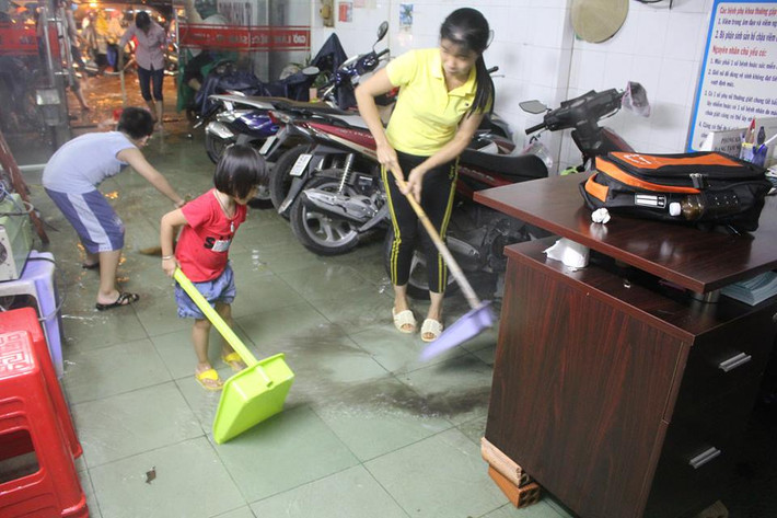 Người dân đẩy nước ra khỏi nhà trên đường (Quận Thủ Đức, TPHCM). Ảnh: Như Sỹ