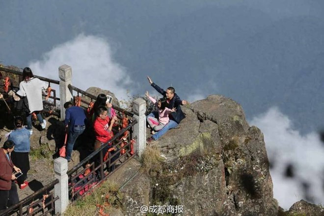Có du khách Trung Quốc "khác người" còn đưa cả trẻ em ra đứng ở mỏm núi chênh vênh để có một tấm ảnh đẹp. (Nguồn: QQ News)