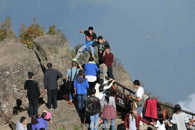 Du khách Trung Quốc mạo hiểm bất chấp biển cảnh báo leo ra ngoài hàng rào để chụp ảnh. (Nguồn: QQ News)