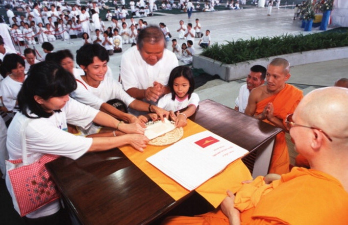 Chùa Dhammakaya được xây dựng nhờ tiền bạc và các lô đất rộng lớn được những người ủng hộ quyên tặng. Ngôi chùa này mở rộng tín đồ theo cách thức khá giống với mô hình tiếp thị đa cấp, nơi tín đồ sẽ được hưởng ưu đãi nếu lôi kéo được người mới. Trong ảnh, sư trụ trì Dhammachayo đang trao chứng nhận cho một gia đình đã quyên góp cho nhà chùa năm 1999. Ảnh: Getty.