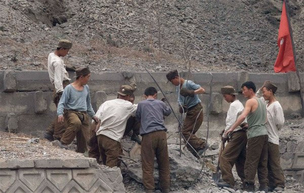 Những nam công nhân vật lộn với khổi bê tông bên đường.