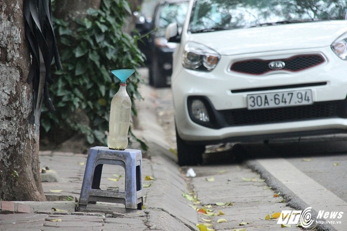 Một tiệm bán xăng ở đường Quán Thánh (Ba Đình, Hà Nội) sử dụng chiếc phễu cùng một chai nhựa nhỏ đặt trên chiếc ghế sát đường để làm dấu hiệu nhận biết. (Ảnh: Tùng Lâm)