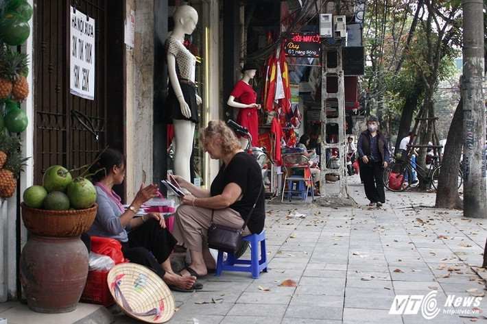 Một hàng bán ảnh (Hà Nội xưa) ngồi ép vào hiên một ngôi nhà trên phố Hàng Bông (Hoàn Kiếm, Hà Nội). (Ảnh: Tùng Lâm)