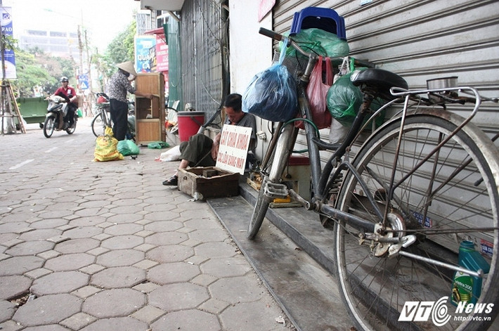 Người thợ sửa khóa trước đây ngồi sát mép đường thì nay ép vào hiên các nhà dân. (Ảnh: Tùng Lâm)