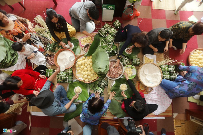 Cả nhà quây quần gói bánh. Các bà vừa làm vừa kể sự tích bánh chưng bánh dày truyền thống của dân tộc vui vẻ.