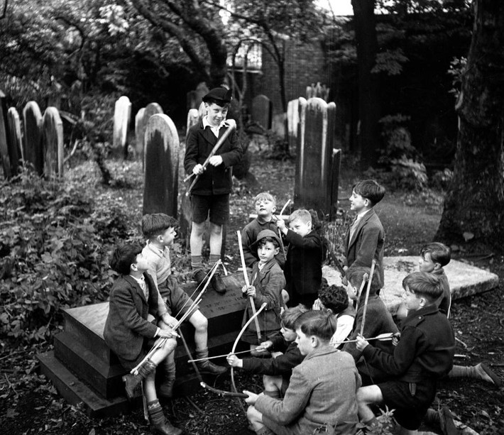 Trong ảnh, các em nhỏ chơi đùa với cung tên trong một nghĩa trang ở Wapping, Đông London, năm 1948.