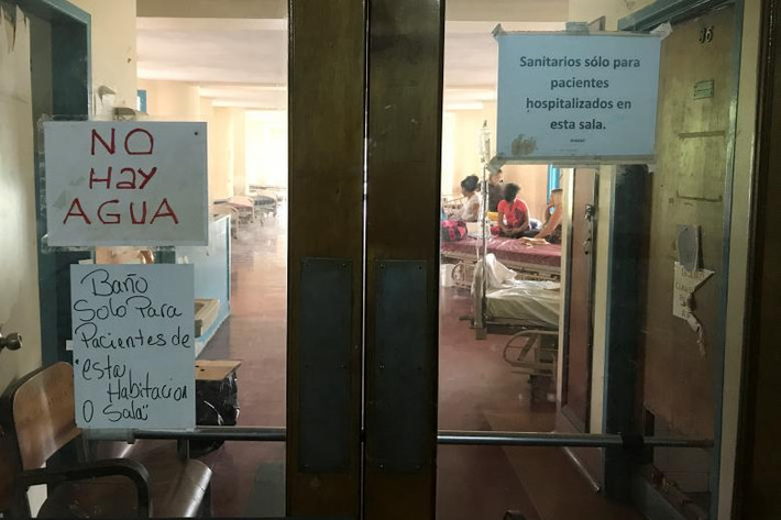 Thông báo “Không có nước” (trái) được dán trên cửa Bệnh viện Đại học Trung ương Venezuela ngày 14/8.