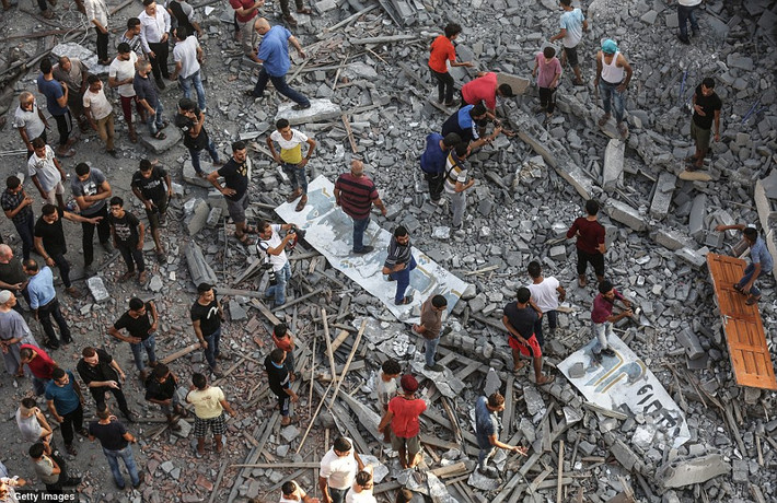 Người dân Gaza tập trung tại một tòa nhà bị phá hủy sau đợt không kích của Israel. Ảnh: Getty.
