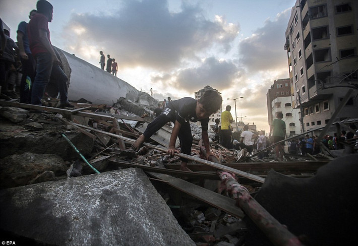 Một em nhỏ đi qua đống đổ nát của tòa nhà trung tâm văn hóa ở Dải Gaza. Ảnh: EPA.