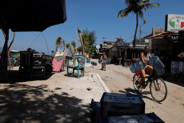 Những du khách này đạp xe đi tìm nước sạch trên đảo Gili Trawangan hôm 9/8. Ảnh: Reuters.