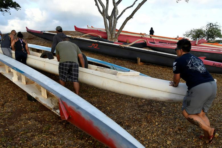 Các thành viên của câu lạc bộ ca nô Alapahoe di chuyển những chiếc ca nô lên vị trí cao hơn ở Honolulu.