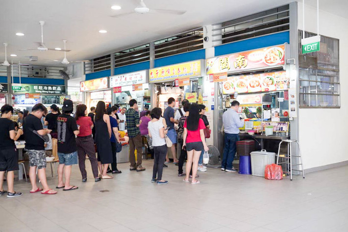 Mọi người xếp hàng mua đồ ăn trước một gian hàng thực phẩm ở Singapore.