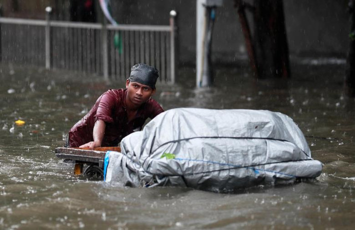Người đàn ông đẩy xe hàng qua con đường ngập nước ở Mumbai ngày 3/7. Ảnh: Reuters.