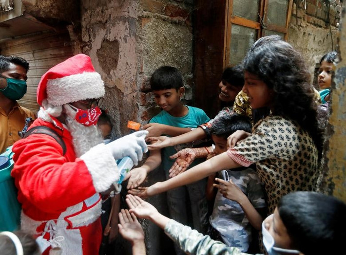 "Ông già Noel" xịt khử trùng tay cho các em nhỏ tại khu ổ chuột ở thành phố Mumbai, Ấn Độ, hôm 19/12.