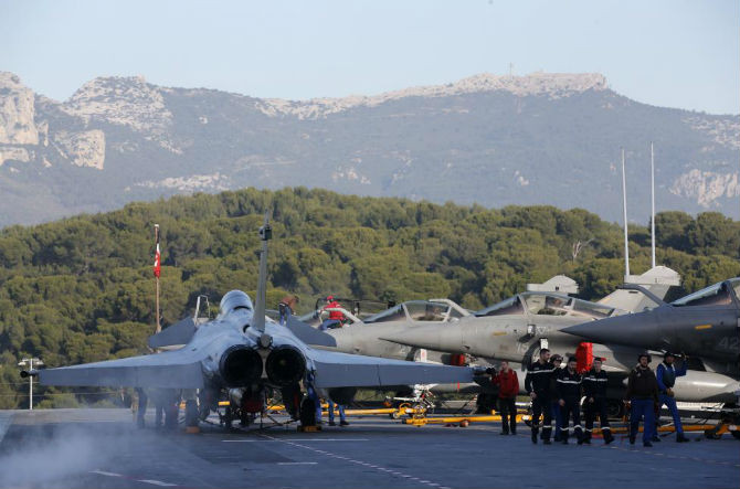 Các thành viên của Hải quân Pháp đi qua các chiến đấu cơ Rafale (phải) trên tàu sân bay Charles de Gaulle.