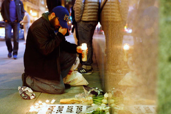 Một người đàn ông quỳ gối và đặt nến bên ngoài Tổng lãnh sự quán Pháp ở San Francisco, California (Mỹ) để tưởng niệm các nạn nhân vụ tấn công khủng bố hôm 13/11.