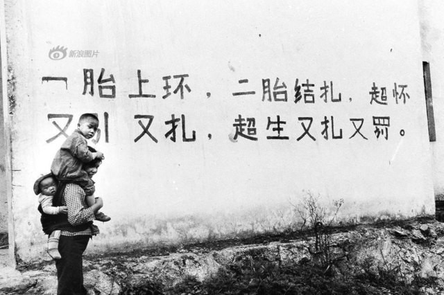 Bức ảnh chụp tại Quý Châu năm 1996. Trên tường là một khẩu hiệu với nội dung: “Sau khi sinh con đầu lòng thì đặt vòng tránh thai, sinh con thứ hai đi thắt ống. Nếu sinh quá quy định sẽ phải phá thai và phạt”.