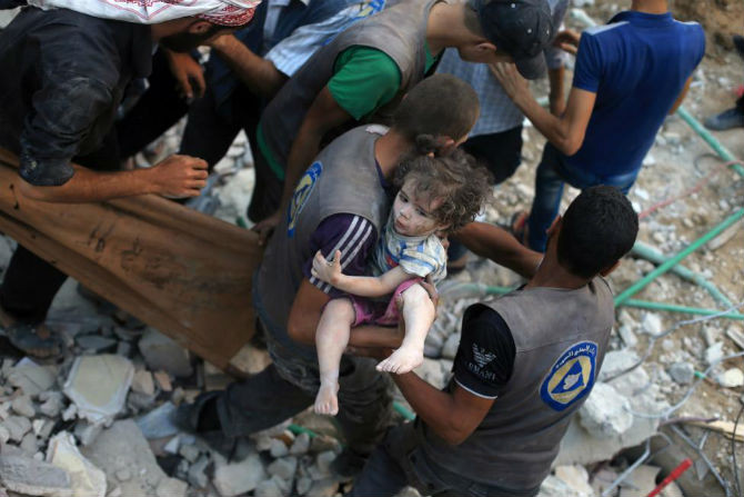 Một bé gái Syria bị thương được đưa ra khỏi đống đổ nát ở Douma, phía đông Ghouta, gần Damascus, ngày 22/8.