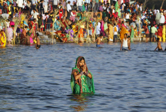Một cô gái theo đạo Hindu lội giữa hồ nước ở Chandigarh, Ấn Độ, để cầu nguyện.