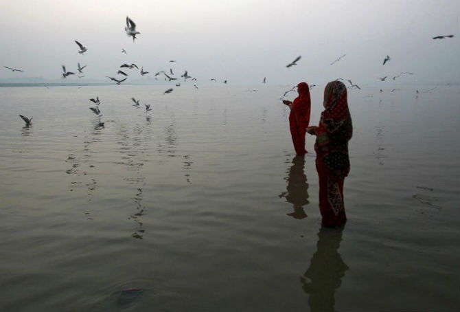 Hai phụ nữ theo đạo Hindu cầu nguyện ở sông Ganga, Allahabad, Ấn Độ, khi họ chờ Mặt trời mọc.