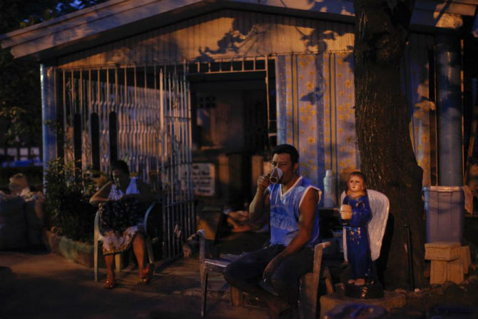 Người đàn ông bình thản uống cà phê vào lúc bình minh tại nghĩa trang Bắc Manila ngày 28/10/2011.