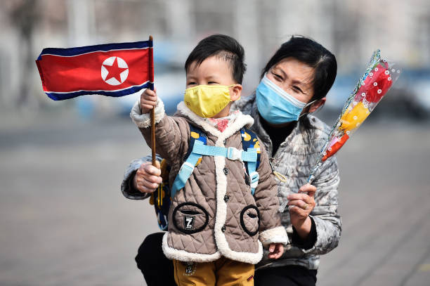 Một người phụ nữ và cháu trai vẫy cờ Triều Tiên tại Bình Nhưỡng ngày 8/3/2023.