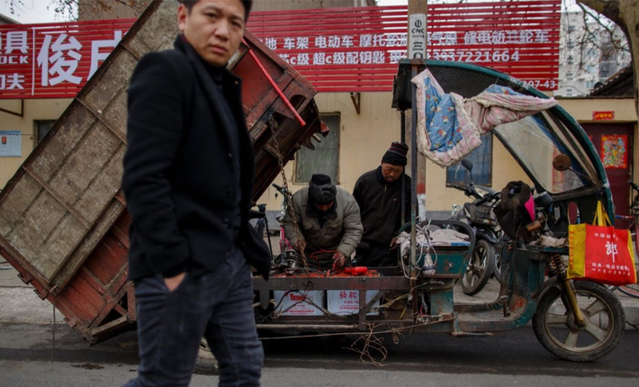 Người đàn ông đi qua cửa hàng sửa xe di động của ông Wang Junchang nằm đối diện một nhà máy thép.