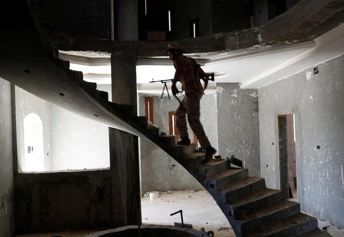 Một chiến binh GNA lục soát bên trong một tòa nhà ở ngoại ô Tripoli hôm 16/5.