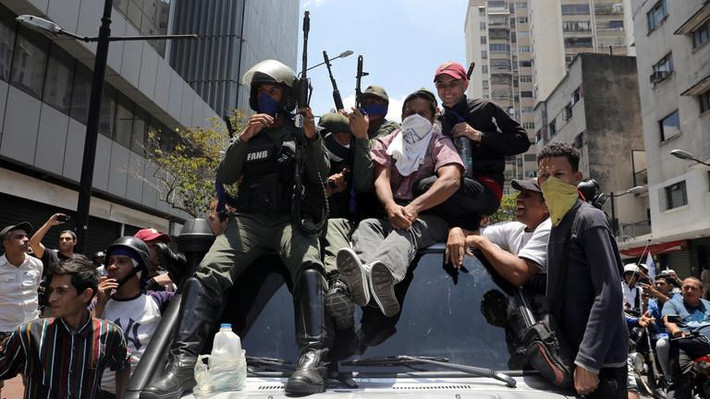 Tổng thống Maduro cùng ngày tuyên bố đã trao đổi với tất cả chỉ huy cấp cao của các lực lượng vũ trang Venezuela. Ông khẳng định quân đội vẫn "tuyệt đối trung thành với chính phủ và tổ quốc". Ông cũng kêu gọi các lực lượng ủng hộ chính phủ xuống đường đáp trả phe đối lập, ngăn chặn nỗ lực chiếm quyền của "tổng thống tự xưng" Juan Guaido. Trong ảnh, người biểu tình chống chính phủ bao vây các quân nhân trung thành với Tổng thống Maduro. Ảnh: Reuters.