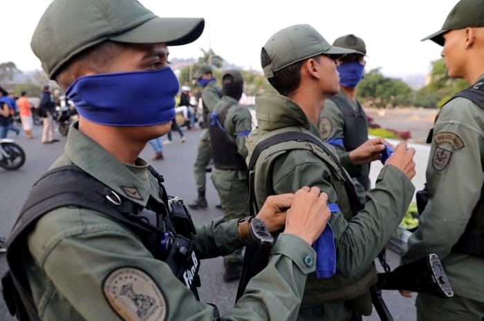 Phe chính phủ khẳng định các quân nhân ủng hộ Juan Guaido chỉ là "một nhóm nhỏ những kẻ phản bội". Bộ Quốc phòng Venezuela đã ra quyết định khai trừ các quân nhân này khỏi hàng ngũ, theo RT. Bộ trưởng Lopez tuyên bố các doanh trại quân sự của nước này vẫn hoạt động bình thường và quân đội quyết tâm bảo vệ "chính phủ hợp pháp". Trong ảnh, các quân nhân ủng hộ phe đối lập đeo khăn màu xanh dương tập trung gần sân bay Caracas sáng 30/4. Ảnh: Reuters.