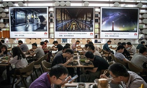 Nhân viên Huawei ăn trưa tại cơ sở Bantian ở Thâm Quyến. Mọi nhu cầu của họ được đáp ứng trong đại bản doanh của Huawei: nhà ở giá rẻ, quán cà phê, phòng tập, khách sạn, phương tiện công cộng, và tàu điện nhập khẩu từ Thụy Sĩ. Ảnh: Getty Images.