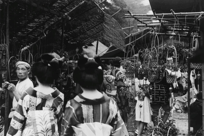 Ông Kuwabara thường tìm sự tương phản. Trong bức ảnh năm 1937, hai geisha đang đi qua chợ hoa truyền thống ở khu Asakusa, lôi cuốn sự chú ý của không chỉ người chụp ảnh mà còn của người bán hàng. Ảnh: Kineo Kuwabara.