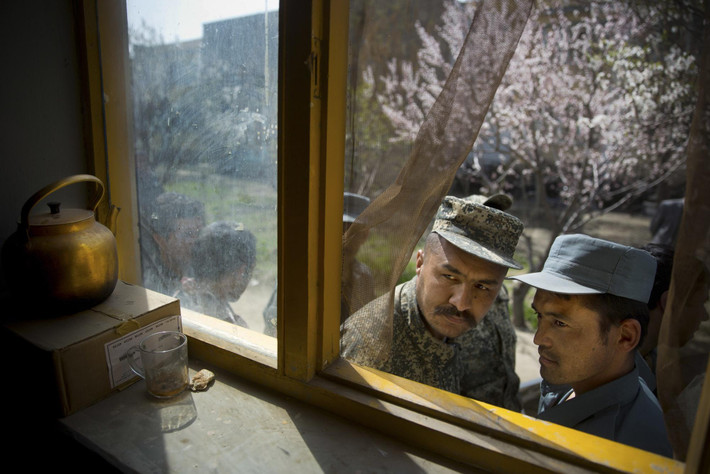 Một người lính Afghanistan (trái) và một cảnh sát đang xếp hàng để đăng ký bỏ phiếu cho cuộc bầu cử tổng thống bên ngoài một ngôi trường ở Kabul ngày 1/4/2014.