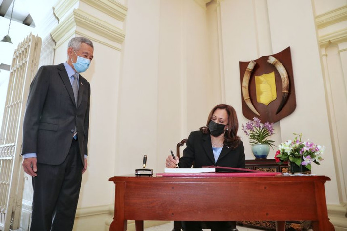 Phó Tổng thống Mỹ Kamala Harris ký tên lên cuốn sổ lưu niệm tại Istana trong khi Thủ tướng Lý Hiển Long đứng cạnh. Ảnh: ST.
