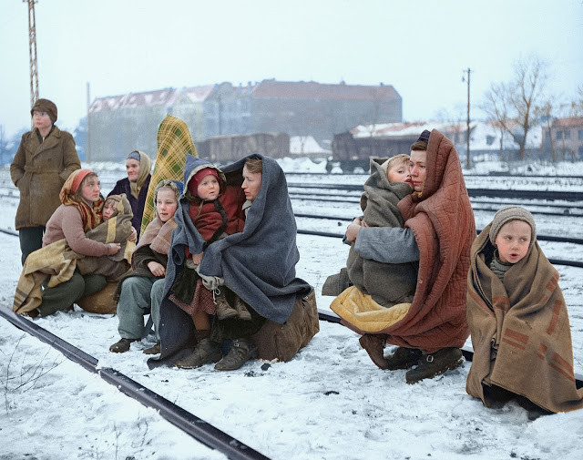 Một số phụ nữ và trẻ em Ba Lan trùm chăn trong lúc ngồi chờ cạnh đường ray tàu ở Berlin Huddle với hy vọng sẽ được lên tàu của Quân đội Anh ngày 14/12/1945.
