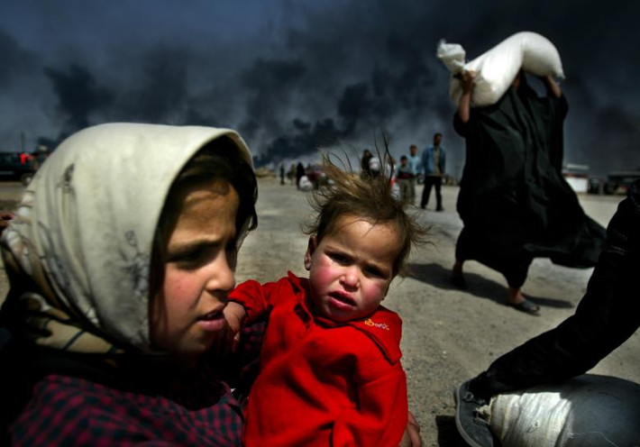 Một bé gái Iraq bế em trong lúc chờ mẹ tại Basra ngày 29/3/2003.