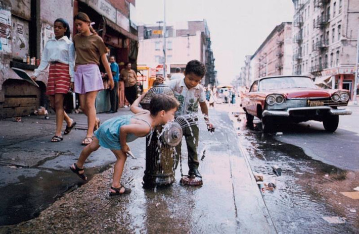 Một em nhỏ uống nước từ vòi nước cứu hỏa trên Đại lộ C ở thành phố New York.