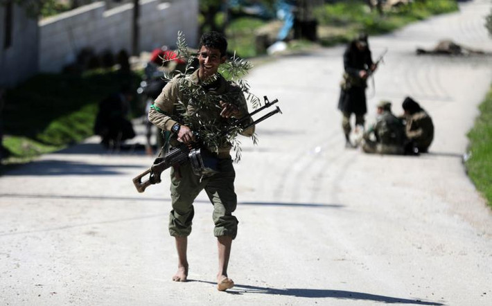 Một chiến binh FSA cầm vũ khí và nhành Ôliu ở phía bắc Afrin ngày 17/3. Ảnh: Reuters.