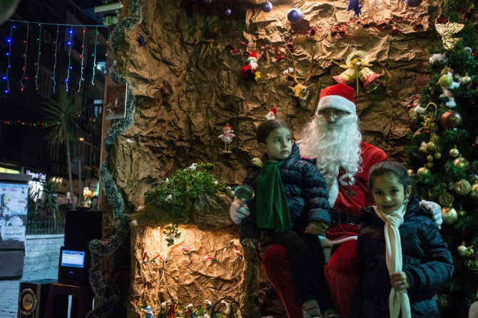 Trẻ nhỏ chụp ảnh cùng “ông già Noel” trong dịp lễ Giáng sinh ở Damascus.